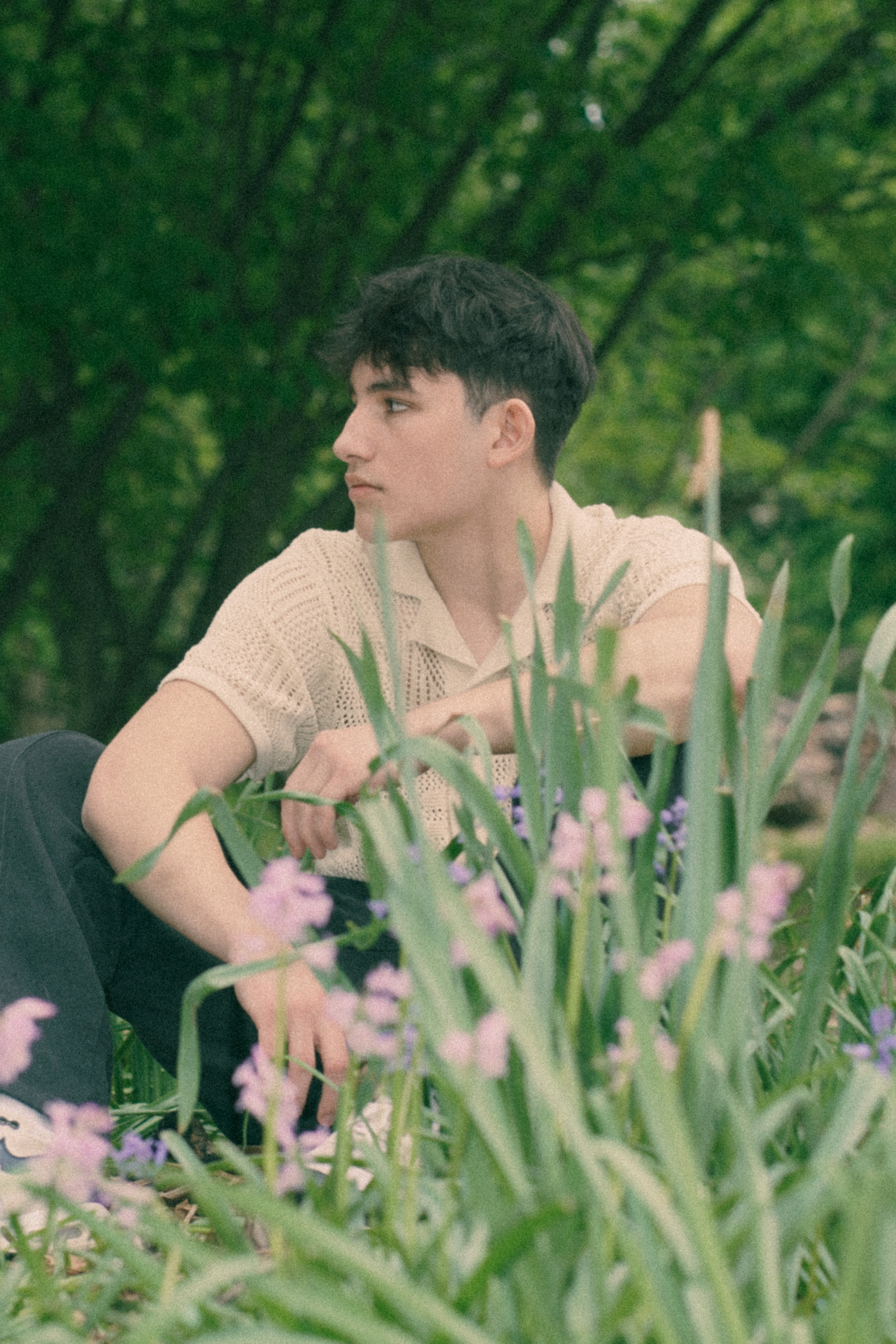 Young man sitting among wildflowers, film inspired portrait