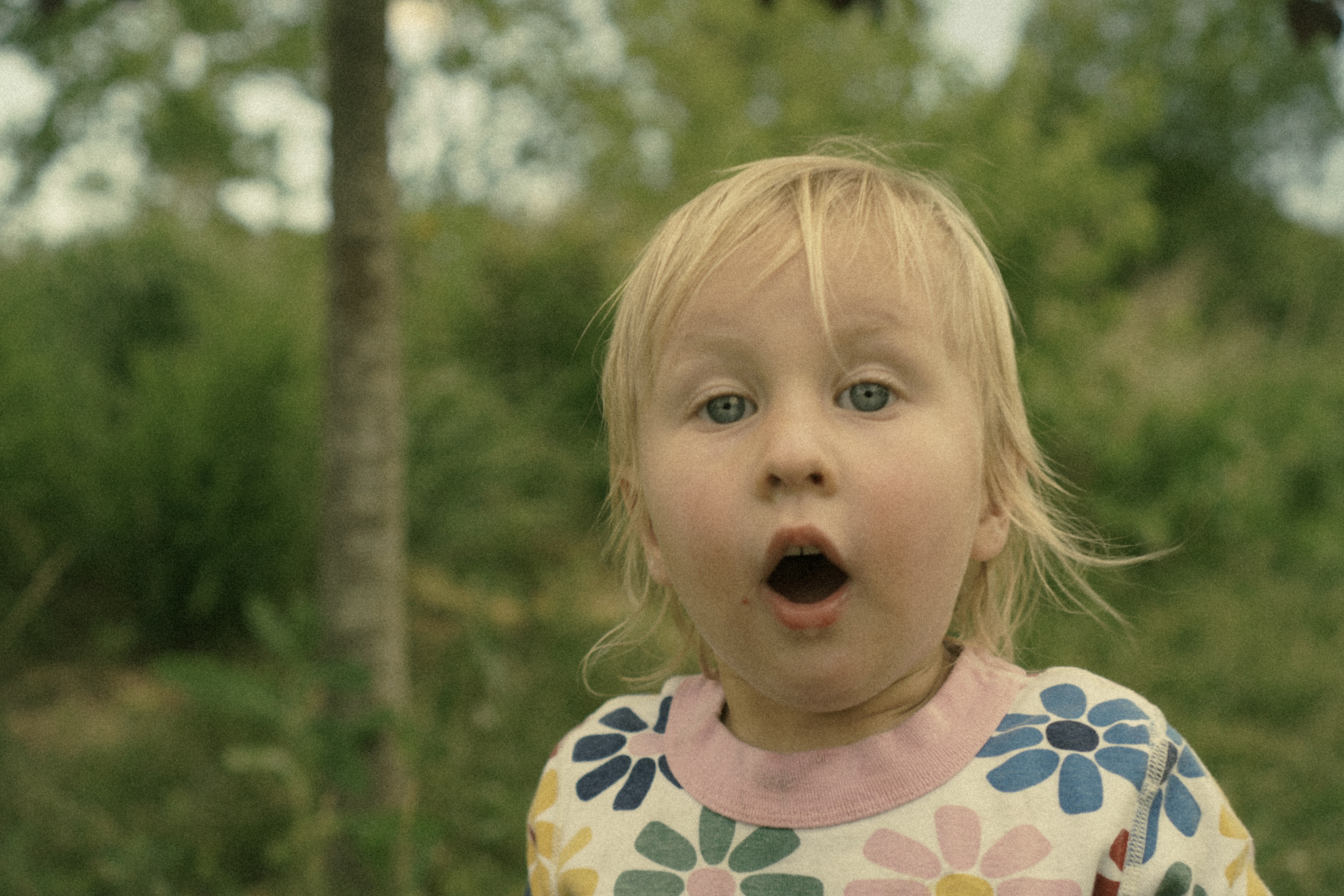 Toddler with a surprised expression in a flower shirt