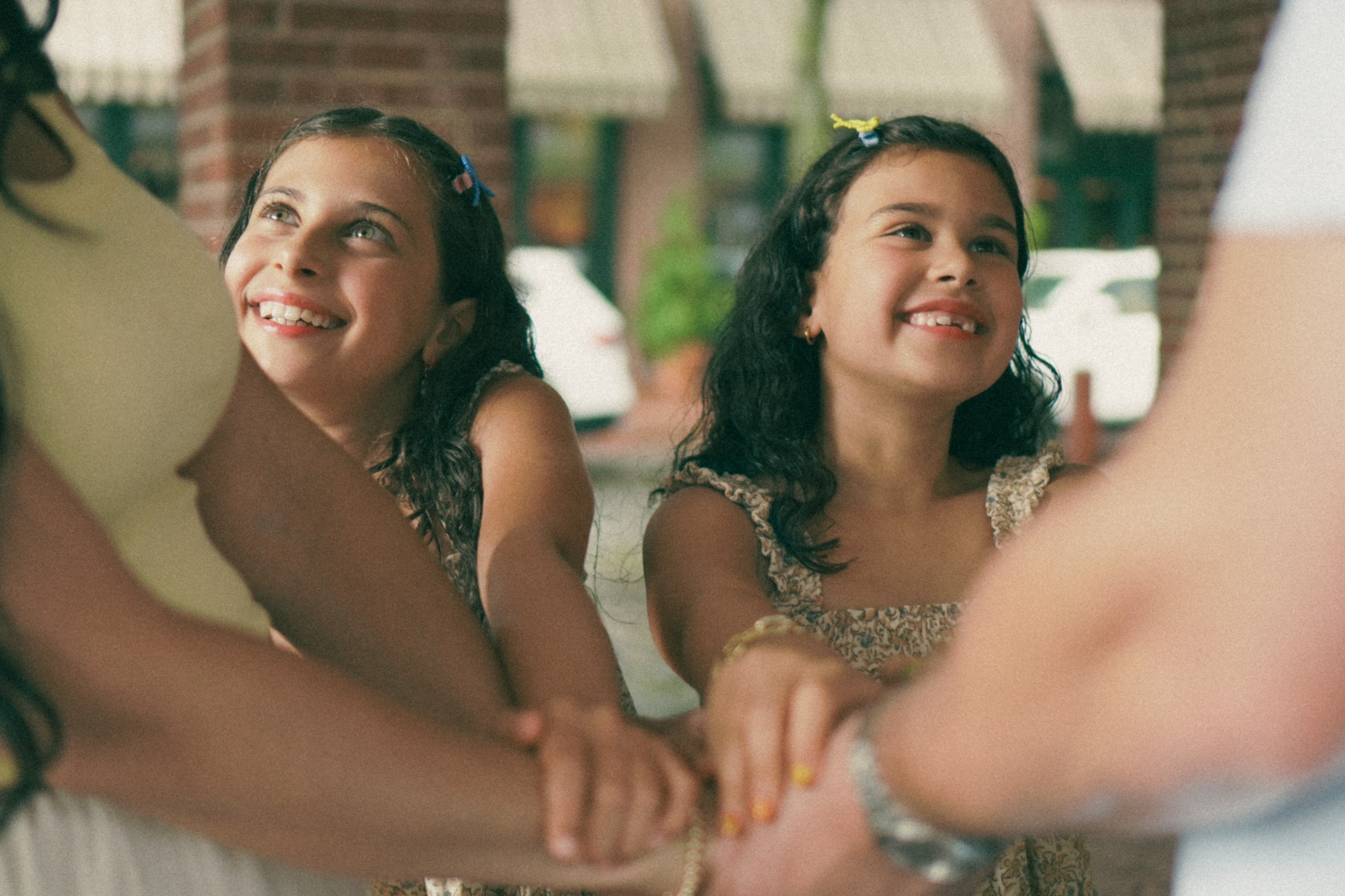 Two girls smiling and holding hands with their parents