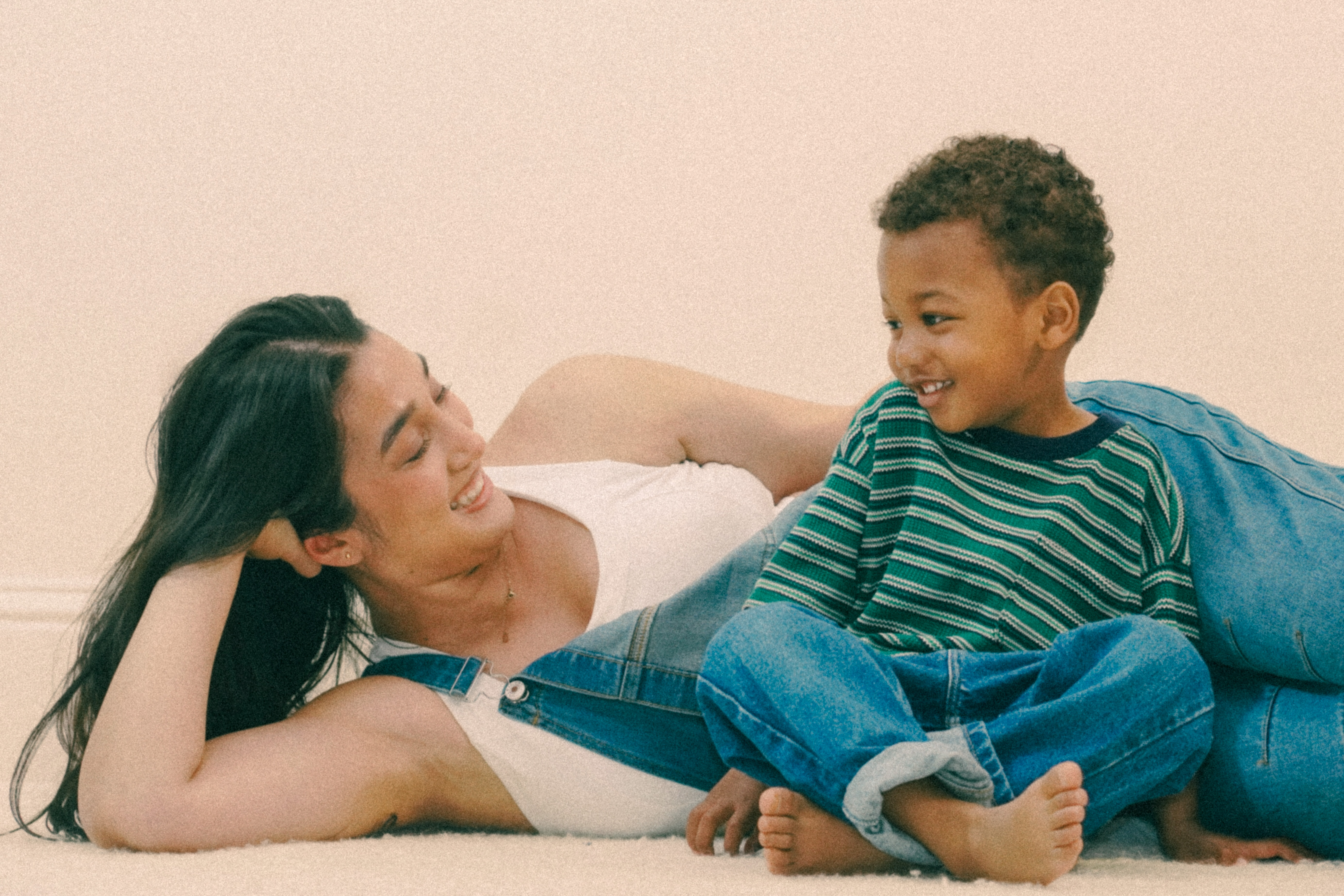 Mom and son in denim overalls laughing on the floor