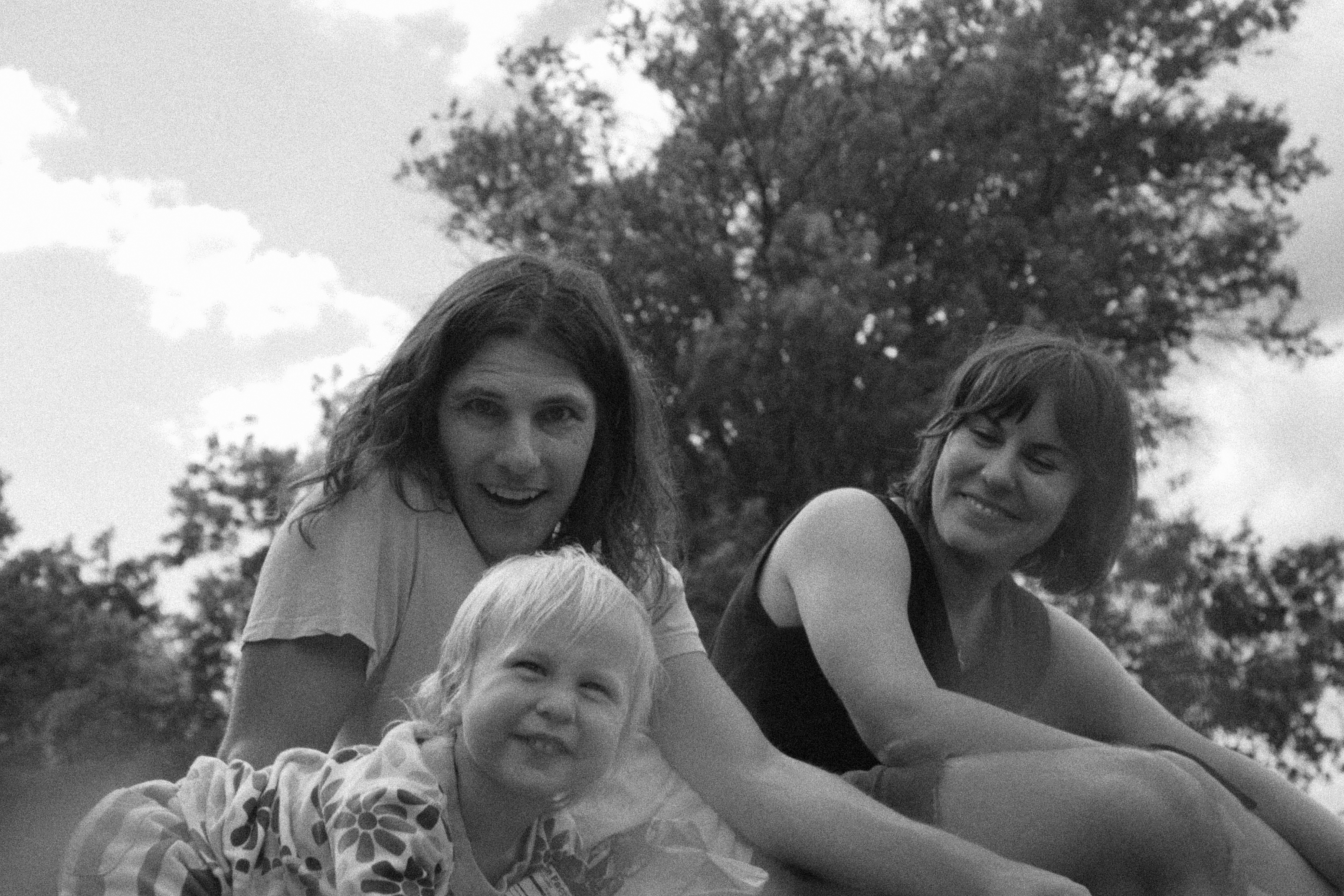 Black and white portrait of a family sitting together under trees